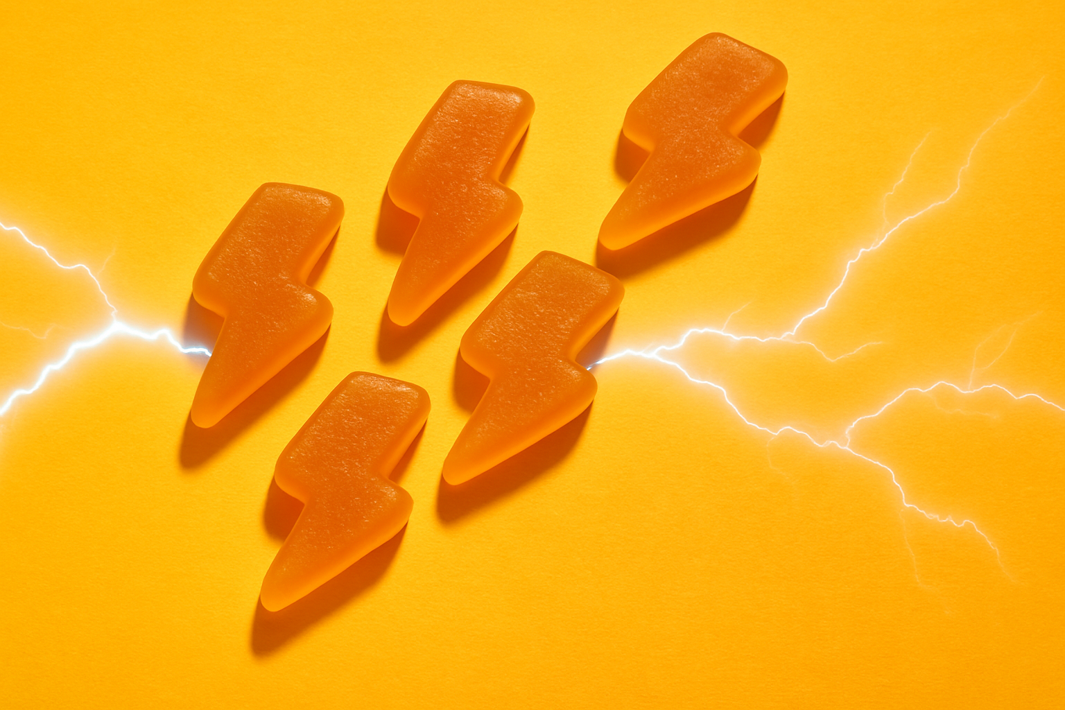 Gummy bear shaped like lightning bolts on a bright yellow background with lightning effects.
